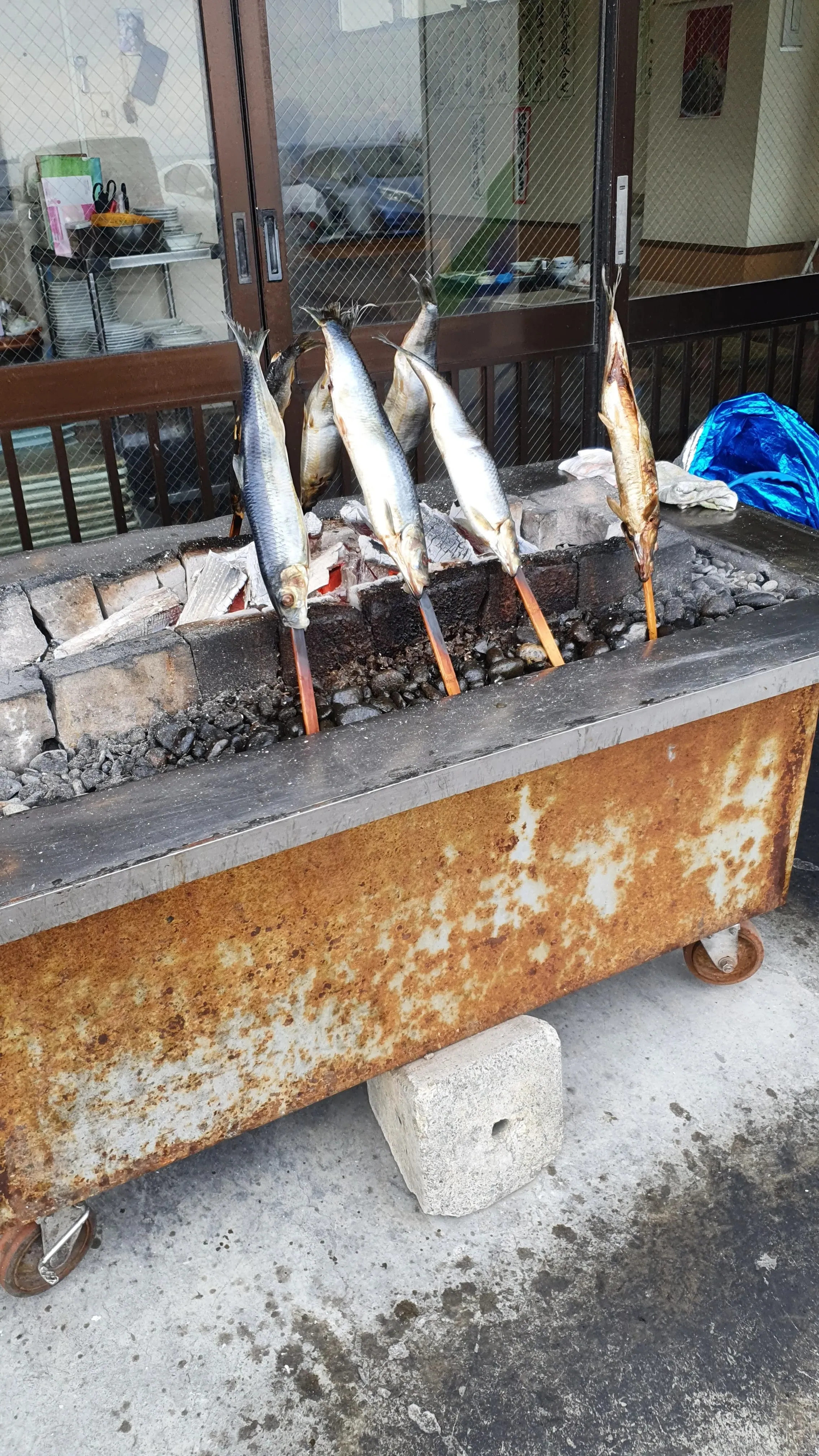 青塚食堂にある巨大なニシンが串刺しで焼かれている写真
